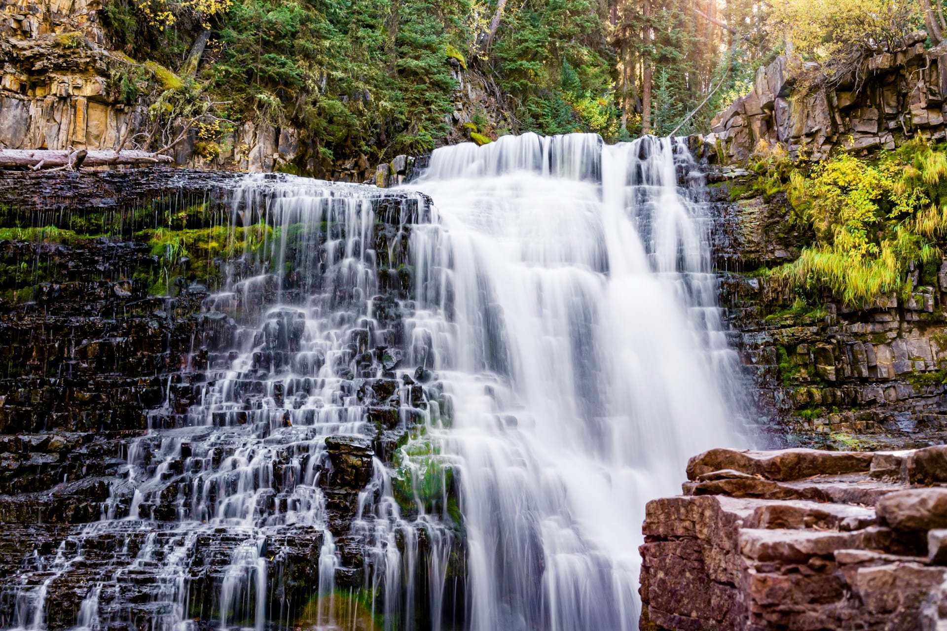 Tiered waterfall cascading over rock ledges in Big Sky, Montana