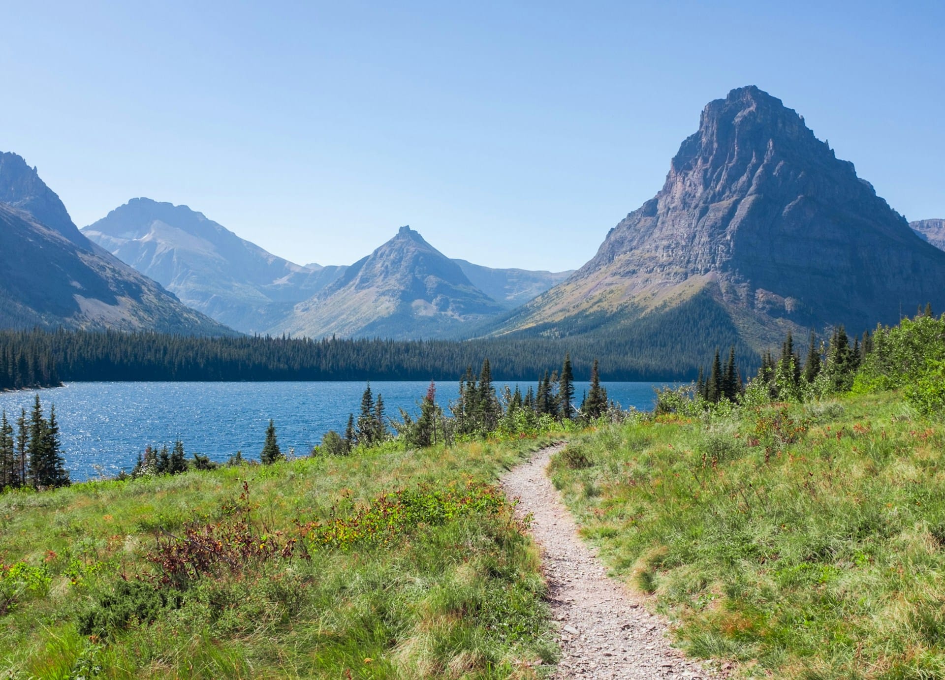 Hiking trail leading toward a lake and mountain peaks in Montana